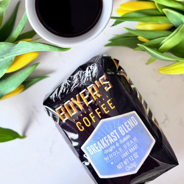Box of Boyer's Coffee Breakfast Blend with a cup of coffee and tulips on a white surface