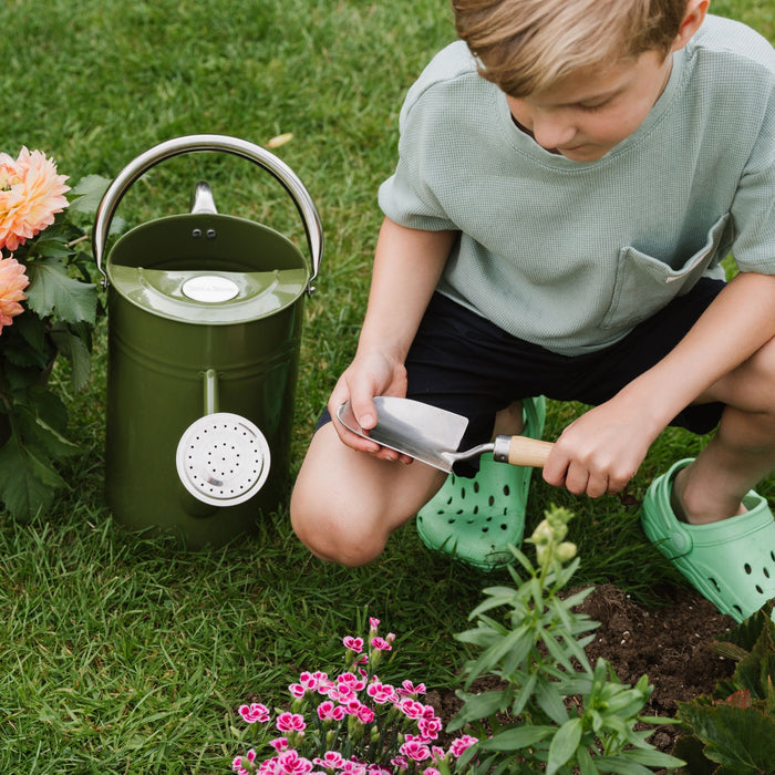 boy holding kids hand trowel whilst planting