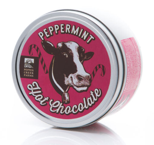 Tin of peppermint hot chocolate with a cow illustration on a white background