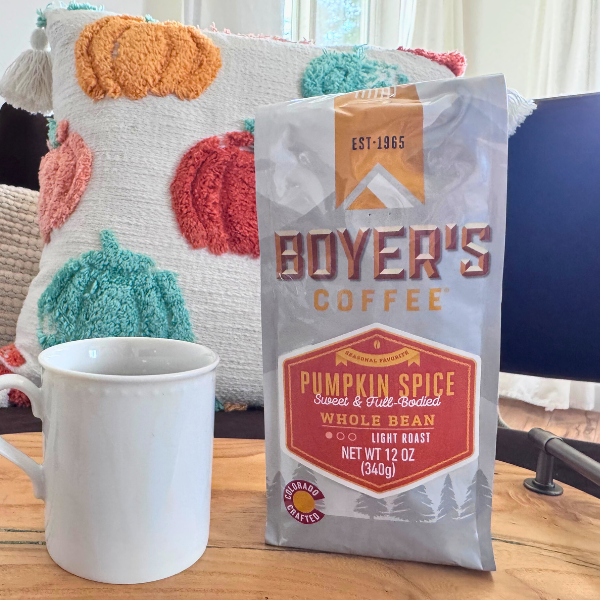 Boyer's Coffee pumpkin spice coffee package on a table with a mug and decorative pillows in the background.