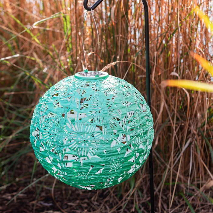 Green decorative lantern hanging among tall grasses
